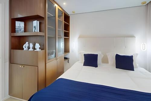 a bedroom with a large white bed with blue pillows at Grand Mercure Itaim Bibi | Premium & Luxury Flat in São Paulo