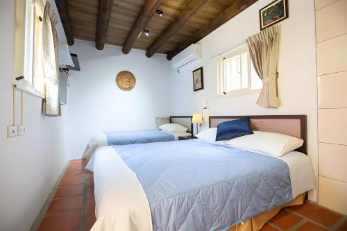 two beds in a bedroom with white walls at 任我行民宿 in Jincheng