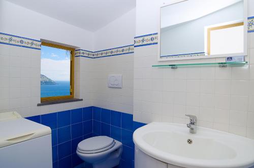 a blue and white bathroom with a toilet and a sink at Casa Hellen Positano center in Positano