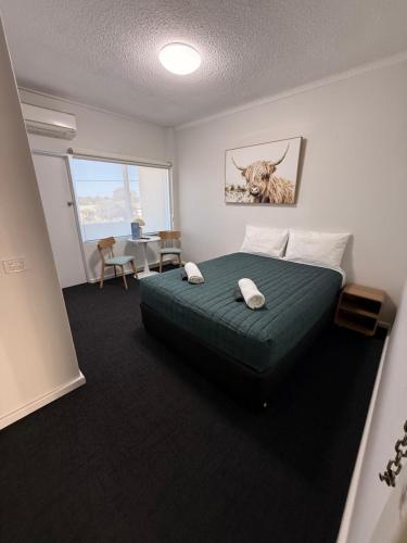 a bedroom with a green bed with a picture of a cow at Manning River Motel in Taree