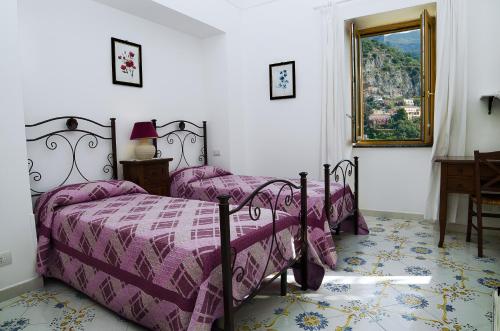 a bedroom with two beds with purple sheets and a window at Casa Hellen Positano center in Positano