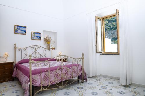 a bedroom with a bed with a purple bedspread and a window at Casa Hellen Positano center in Positano