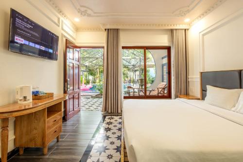a bedroom with a bed and a desk with a television at Trương Nhi Bungalow in Phú Quốc