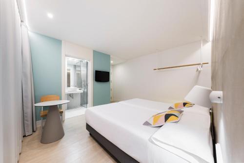 a white bedroom with a bed and a table at Hotel Mar del Plata in A Coruña