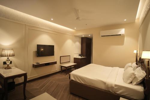 a hotel room with a bed and a television at Regent Park Hotel in Jalandhar