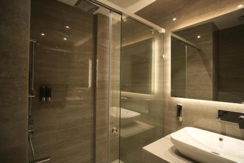 a bathroom with a glass shower and a sink at Regent Park Hotel in Jalandhar