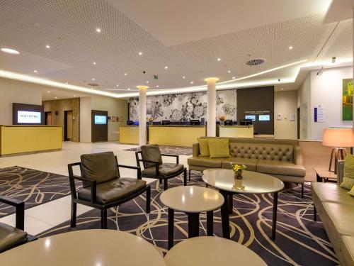 a lobby with a waiting room with tables and chairs at Novotel Nürnberg Centre Ville in Nuremberg