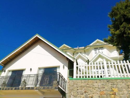 a white house with a fence and a balcony at Melford Nuwaraeliya in Nuwara Eliya