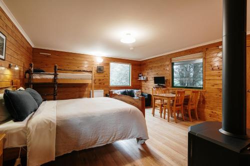 a bedroom with wooden walls and a bed and a table at Cradle Highlander in Cradle Mountain