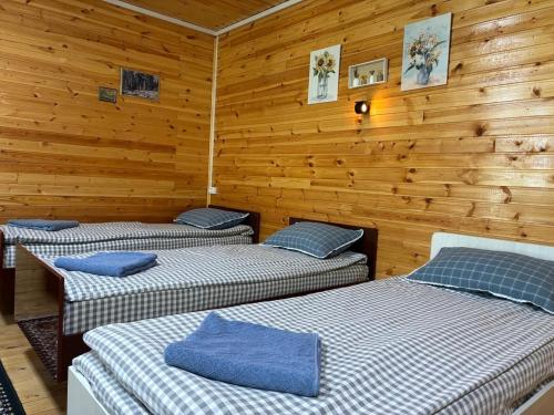 three beds in a room with wooden walls at Мачу Пикчу in Cholpon-Ata
