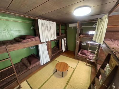 a room with three bunk beds and a table at Backpacker's House Kamome in Fujiyoshida