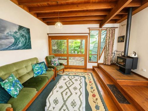 a living room with a couch and a tv at Cottage on the Lake - peaceful Burrill Lake escape in Burrill Lake