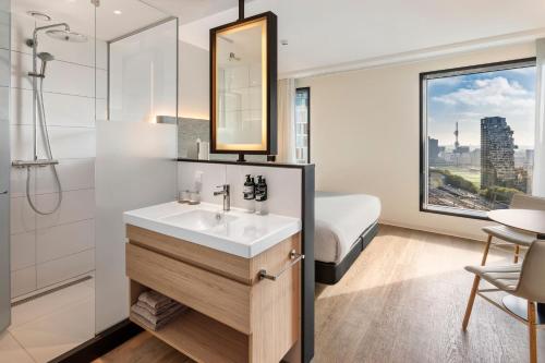 a bathroom with a sink and a mirror and a bed at INNSiDE by Meliá Amsterdam in Amsterdam