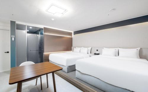 a hotel room with two beds and a desk and a table at Brown Dot Hotel Daecheon Beach, Boryeong in Boryeong