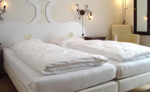 a white bed with two white pillows on it at Hotel Huys van Heusden in Asten