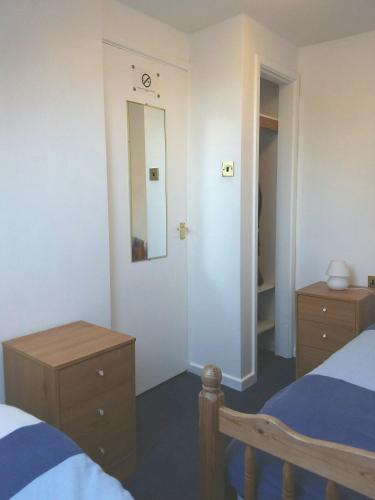 a bedroom with a bed and a dresser and a mirror at Salty Smiles Cottage in Penzance