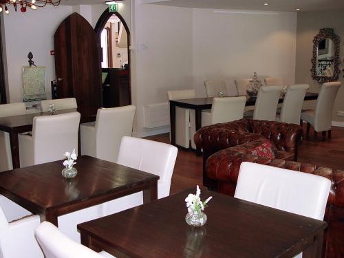a living room with couches and tables and white chairs at Hotel Huys van Heusden in Asten
