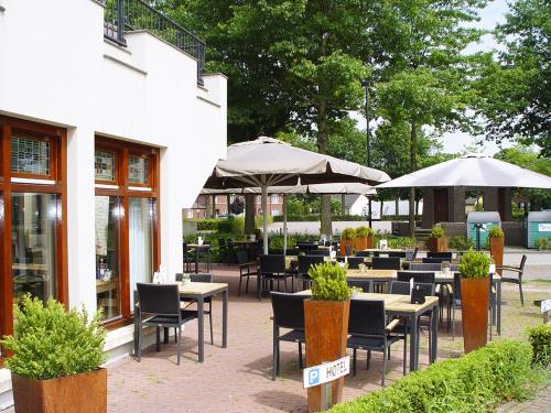 a restaurant with tables and chairs and umbrellas at Hotel Huys van Heusden in Asten