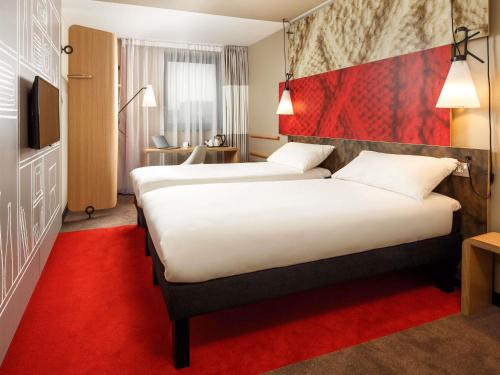 a hotel room with two beds and a red carpet at ibis Cambridge Central Station in Cambridge