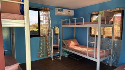 a room with three bunk beds and a blue wall at BalaiBesa Transient House in Lingayen