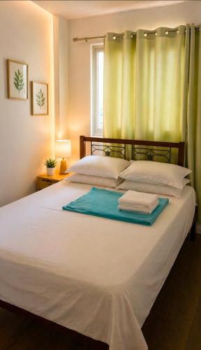 a bedroom with a large white bed with a window at Alabang Staycation by East Bay Residence in Sampong