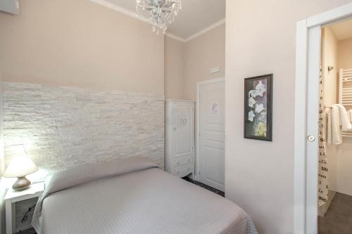 a white bedroom with a bed and a chandelier at Hotel Masaccio in Florence