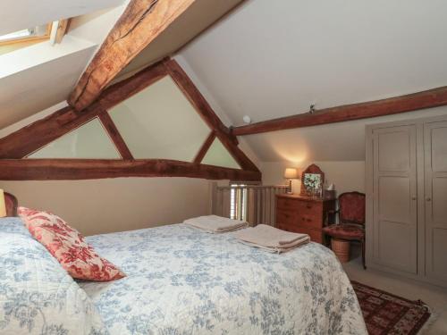 a bedroom with a bed in a room with wooden beams at The Lodge Farm Barn in Kerne Bridge