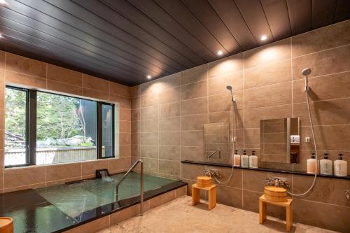 a bathroom with a tub and a glass shower at Yumoto Onsen OharaSansou in Kyoto