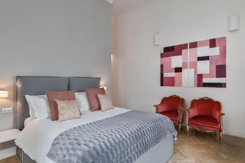 a bedroom with a bed and two red chairs at DA ME Suites in Rome