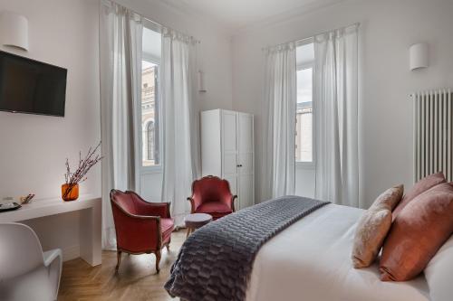 een slaapkamer met een bed, een bureau en stoelen bij DA ME Suites in Rome