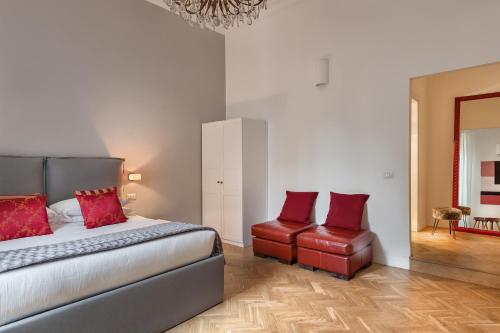 a bedroom with a bed and two red chairs at DA ME Suites in Rome