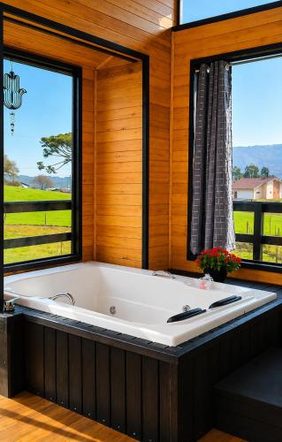 a large bath tub in a room with two windows at Pé na Picada in Urubici