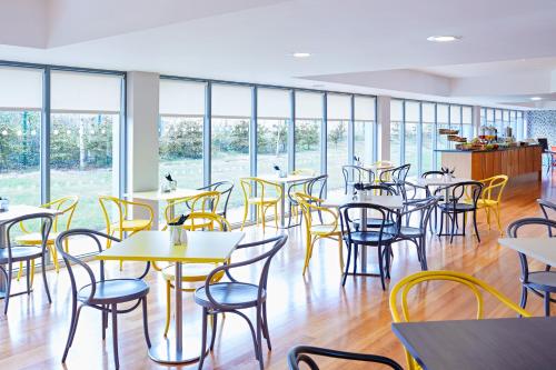 a dining room with tables and chairs and windows at ibis Styles Barnsley in Barnsley