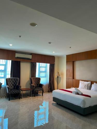 a hotel room with a large bed and chairs at Utc Damhil By Prasanthi in Telaga
