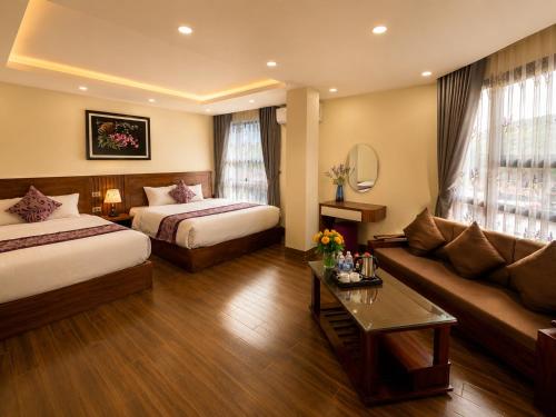 a hotel room with two beds and a couch at Lavender SaPa Hotell & Spa - Free foot soak service in Sapa
