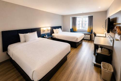 a hotel room with two beds and a television at Microtel Inn & Suites by Wyndham Macon in Wesleyan Hills