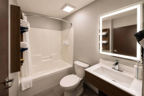 a bathroom with a toilet and a sink and a tub at Microtel Inn & Suites by Wyndham Macon in Wesleyan Hills
