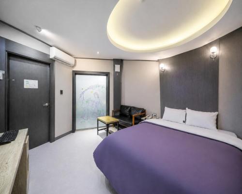 a hotel room with a large bed and a chair at Hotel Midas in Daegu