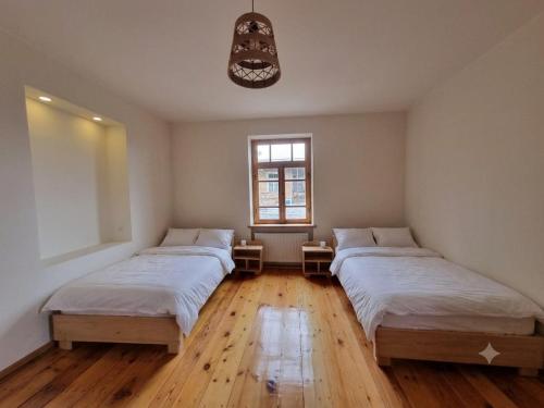 two beds in a room with wooden floors and a window at kakhtubani in Chandari