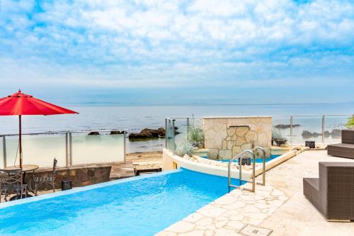a swimming pool with an umbrella next to the ocean at ヴィラモンタン・淡路 in Akashi