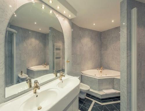 a bathroom with two sinks and a tub and a toilet at Sunday Hotel Schloss Neustadt Glewe in Neustadt-Glewe