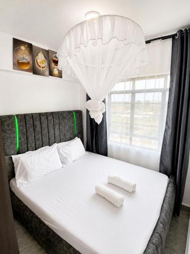 a bedroom with a white bed with two towels on it at Calvin's corner in Kisumu