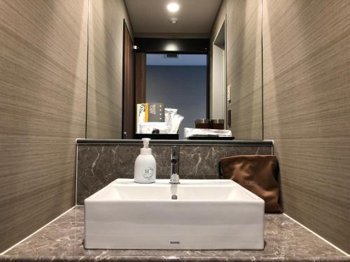 a bathroom with a white sink and a mirror at REX HOTEL Beppu in Beppu