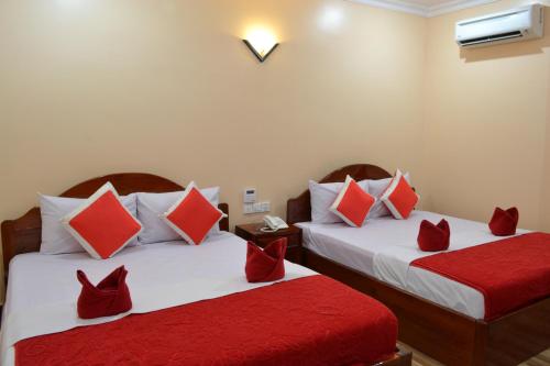 two beds in a room with red and white pillows at Capital Battambang Hotel in Battambang