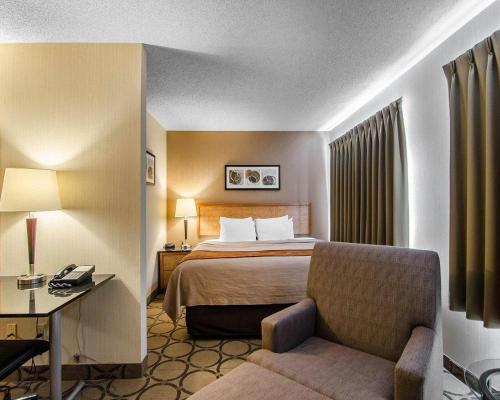 a hotel room with a bed and a chair at Comfort Inn Regina East in Regina
