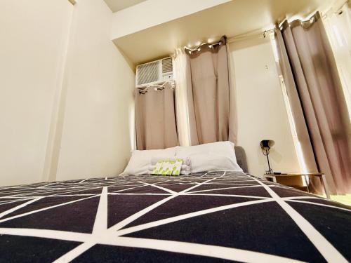 a bedroom with a black and white bed with curtains at JFam Suites, C4-11K Studio, Up To 4 Pax in Biñan