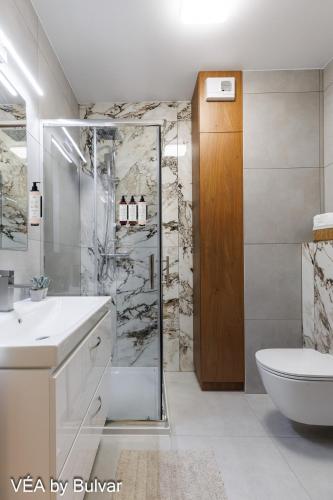 a bathroom with a shower and a toilet and a sink at VÉA by Bulvar in Kielce
