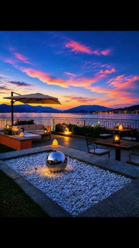 a patio with a fire pit with a sunset in the background at Resort Antico Verbano in Meina