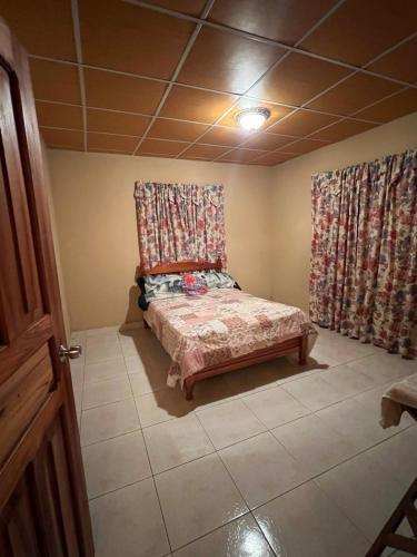 a small bedroom with a bed in a room with curtains at Comfortable 3-bedroom, 1-kitchen cottage in Cerro Punta