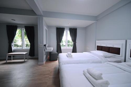 two white beds in a room with windows at Stay C Hotel in Ban Samet